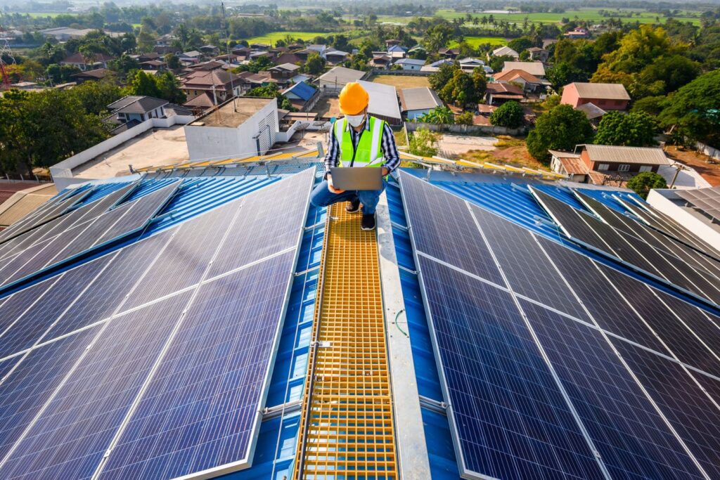 os engenheiros usam um laptop para examinar os paineis solares no telhado de uma casa onde os paineis solares sao instalados usando energia solar 1 1 1